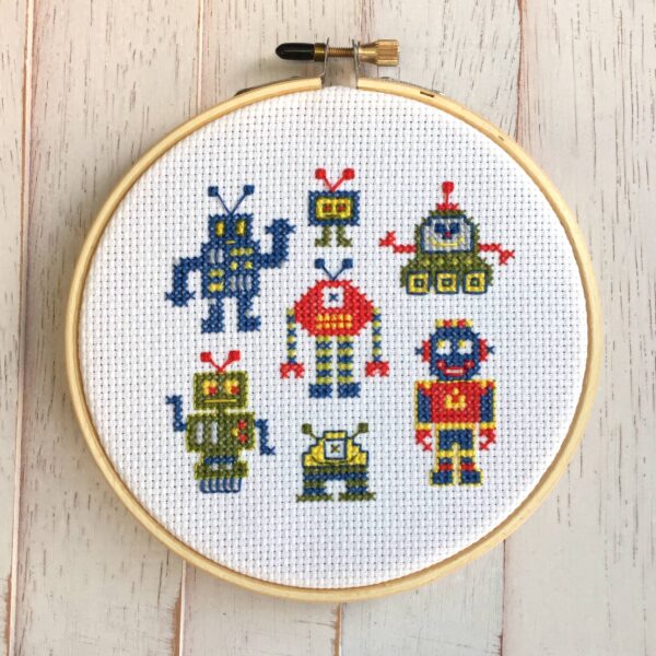 Robots cross-stitch on white aida cloth